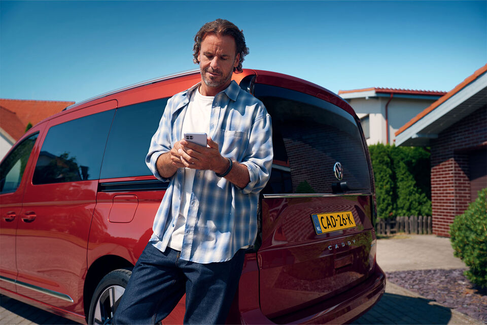 Caddy Kombi leundend met telefoon in handen